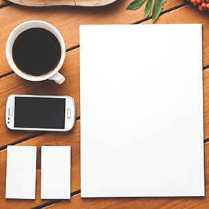 Wooden desktop with coffee, a phone, and a notepad